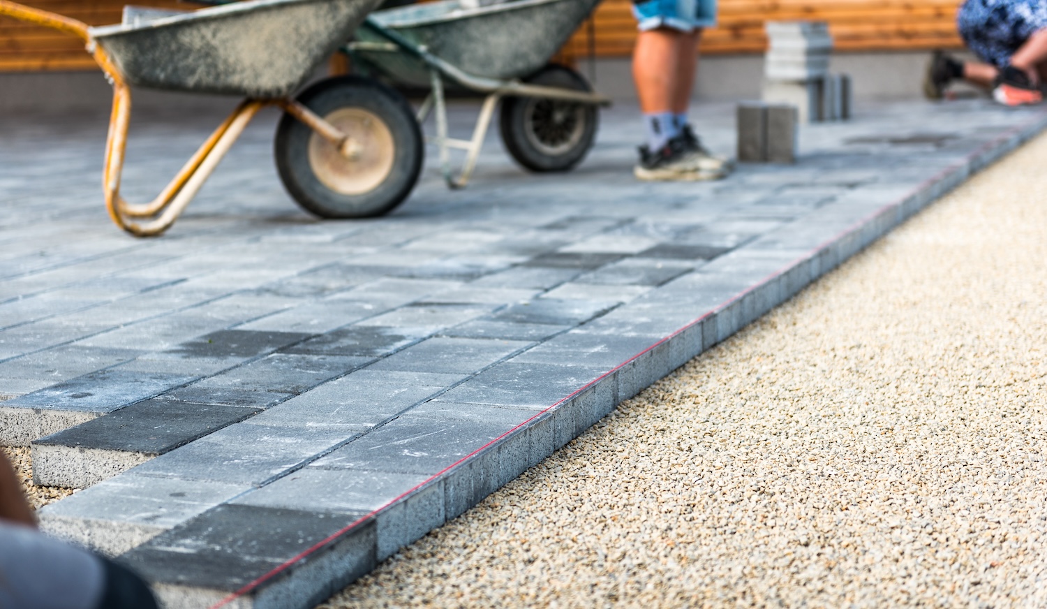 Laying a brick driveway A brick driveway with two wheelbarrows and a man pictured in the background.